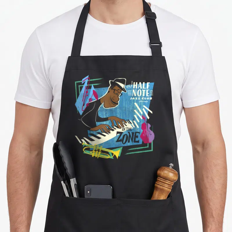 Soul jazz apron - Retro pianist playing keys with text The HALF NOTE JAZZ CLUB presents IN THE ZONE and scattered — shown on a black cotton canvas apron against a white background