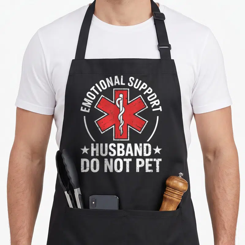 Emotional husband wife aprons - Red Star of Life with white EMOTIONAL SUPPORT HUSBAND DO NOT PET text in distressed — shown on a black cotton canvas apron against a white background