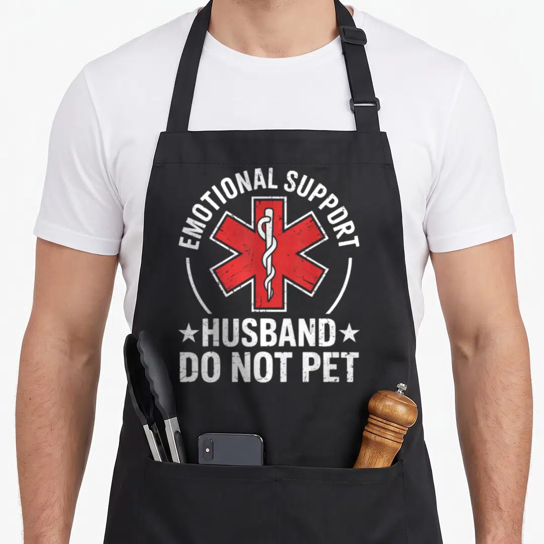 Emotional husband wife aprons - Red Star of Life with white EMOTIONAL SUPPORT HUSBAND DO NOT PET text in distressed — shown on a black cotton canvas apron against a white background