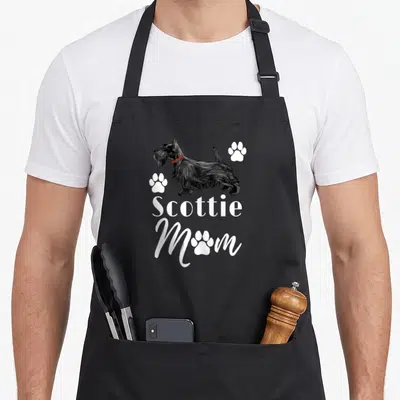 Scottish terrier scottie dog apron - Black Scottish Terrier with red plaid collar and white Scottie Mom text surrounded — shown on a black cotton canvas apron against a white background