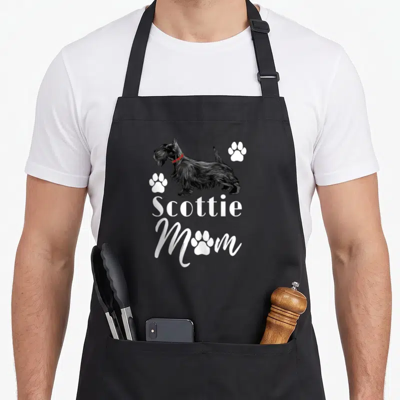 Scottish terrier scottie dog apron - Black Scottish Terrier with red plaid collar and white Scottie Mom text surrounded — shown on a black cotton canvas apron against a white background