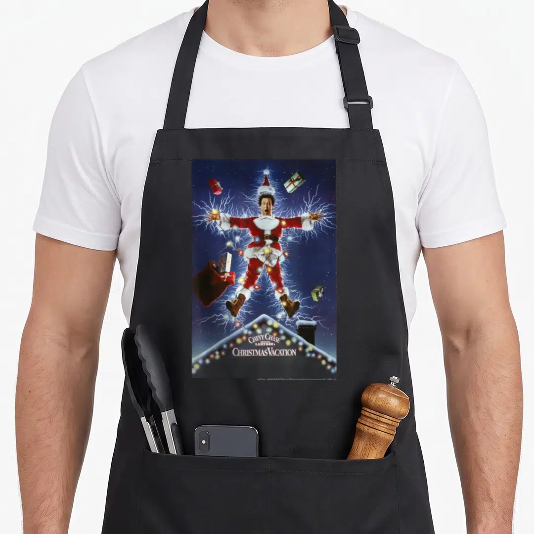 Movie national lampoon's christmas vacation apron - Man in Santa suit struck by lightning above snowy roof with stacked — shown on a black cotton canvas apron against a white background