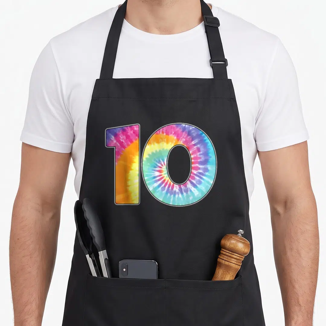Number tie-dye apron - Digit 10 filled with pink yellow blue purple and green tie-dye pattern — shown on a black cotton canvas apron against a white background