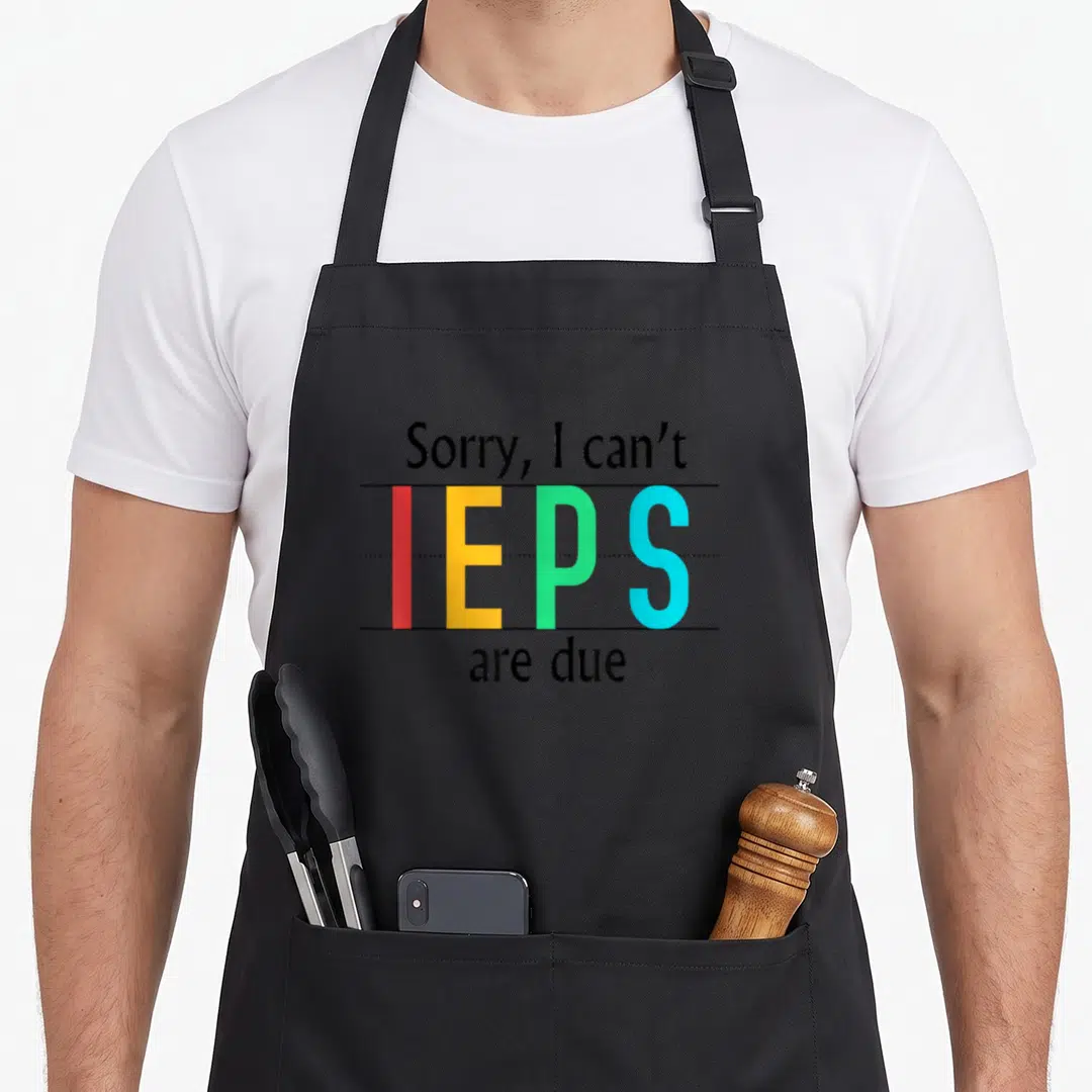 Tag teacher apron - Stacked text Sorry IEPs are due with red yellow green blue letters between black lines — shown on a black cotton canvas apron against a white background