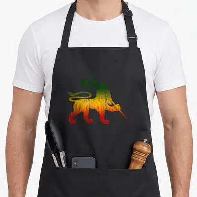 Judah rastafari lions apron - Distressed lion holding flag in green yellow red gradient — shown on a black cotton canvas apron against a white background