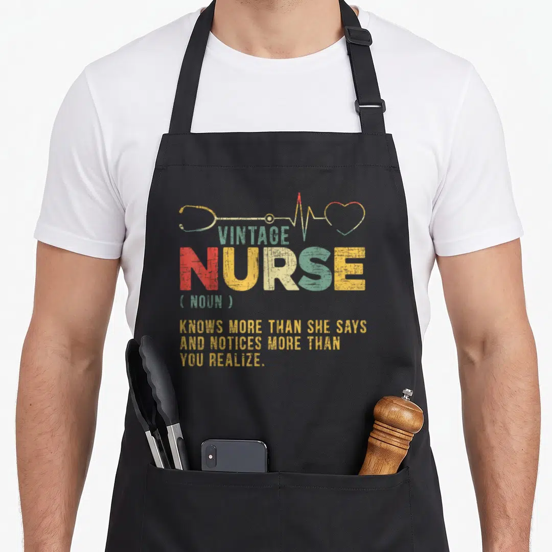 Definition nursing apron - Vintage nurse dictionary definition text with stethoscope and heartbeat line in olive green — shown on a black cotton canvas apron against a white background