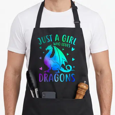 Funny dragon apron - Cartoon dragon in purple and blue gradients with Just A Girl Who Loves Dragons text and scattered — shown on a black cotton canvas apron against a white background