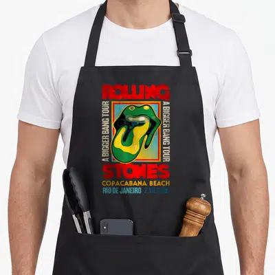Bigger rolling stones apron - Retro tongue logo with A Bigger Bang Tour text and Copacabana Beach date — shown on a black cotton canvas apron against a white background