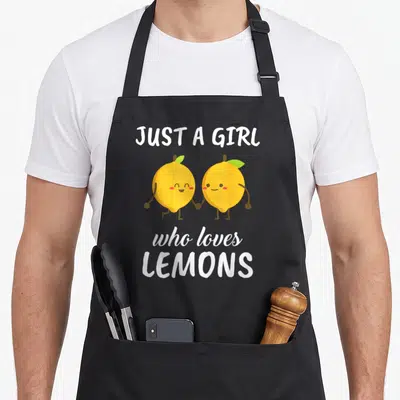 Clothe lemon apron - Two cartoon lemons holding hands with white text JUST A GIRL who loves LEMONS — shown on a black cotton canvas apron against a white background