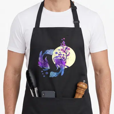 Moon cherry apron - Two purple blue koi fish circle pale yellow moon with pink cherry blossoms watercolor — shown on a black cotton canvas apron against a white background