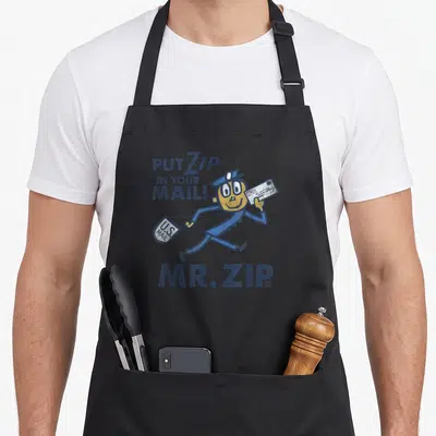 Funny zip usps aprons - Retro Mr. Zip character running with mail bag and slogan text — shown on a black cotton canvas apron against a white background