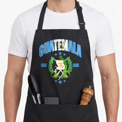 Flag bird apron - Guatemala coat of arms with quetzal bird, LIBERTAD scroll, and crossed rifles in blue white green — shown on a black cotton canvas apron against a white background