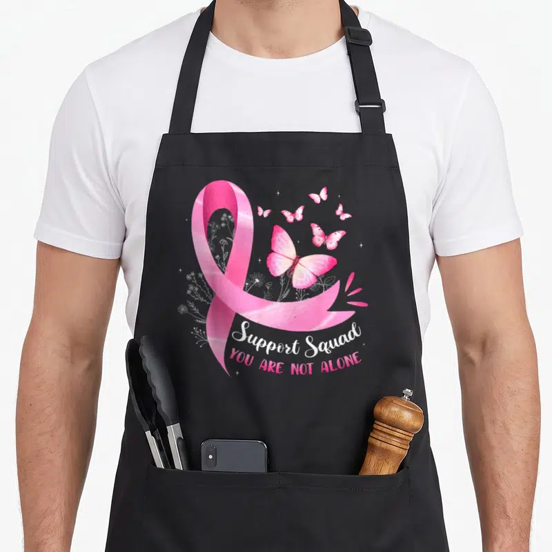 Bow breast cancer awareness aprons - Pink watercolor ribbon with butterflies and Support Squad text on black apron — shown on a black cotton canvas apron against a white background