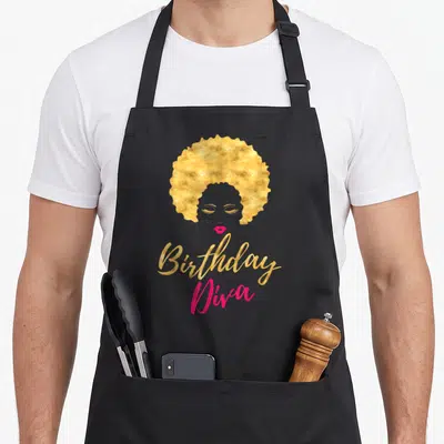 Birthday hair apron - Gold afro woman silhouette with pink lips and Birthday Diva text on grey — shown on a black cotton canvas apron against a white background