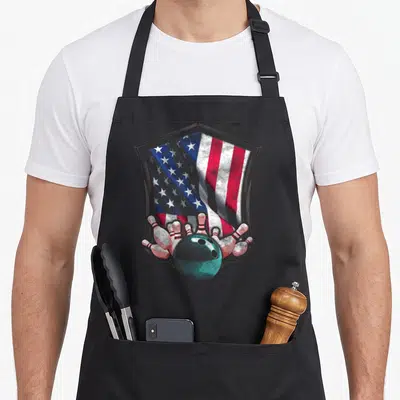 Bowling 4th of july apron - Teal bowling ball and red white blue flag inside grey shield border — shown on a black cotton canvas apron against a white background