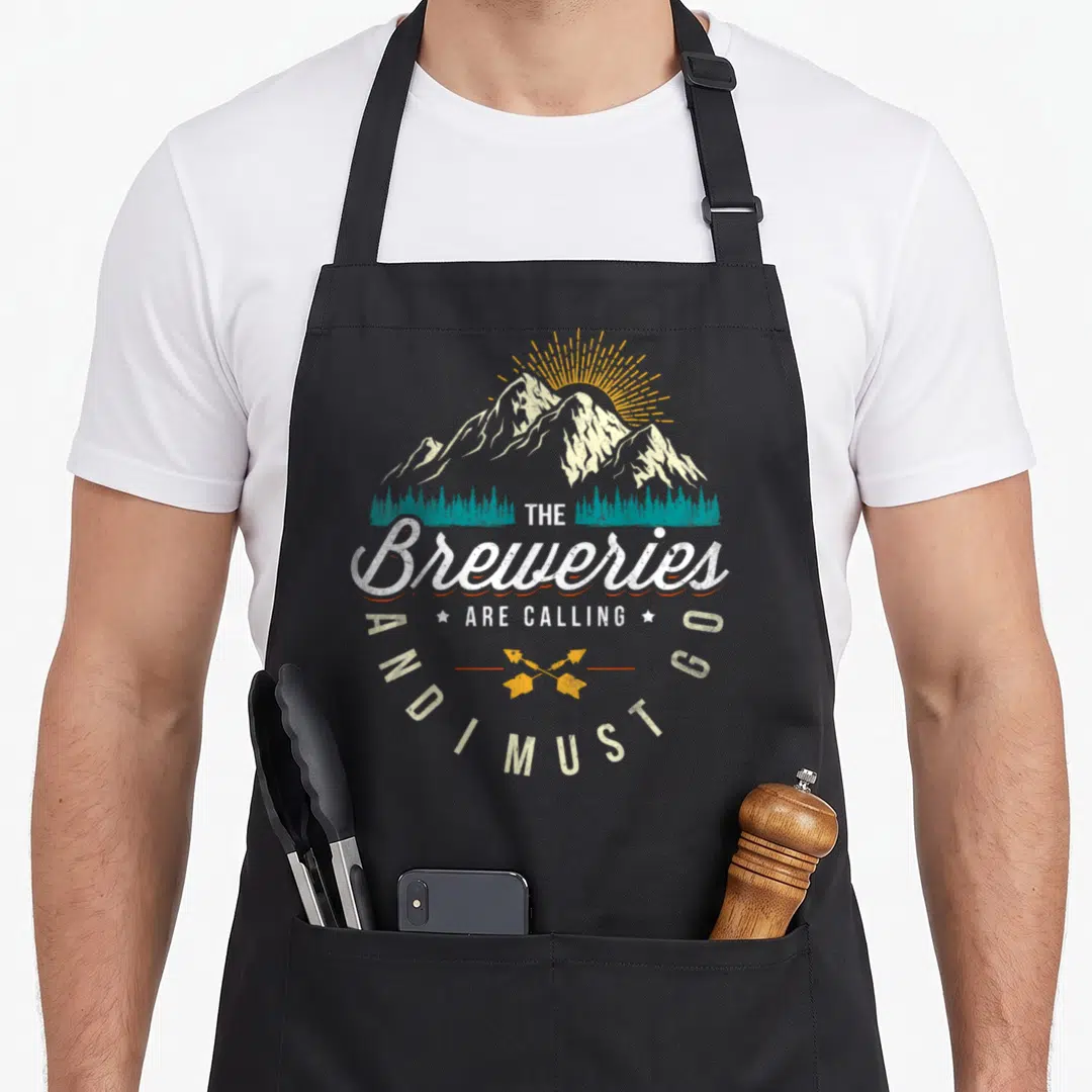 Brewery brewers apron - Retro mountain scene with teal trees, yellow sunburst, crossed arrows and THE Breweries ARE — shown on a black cotton canvas apron against a white background