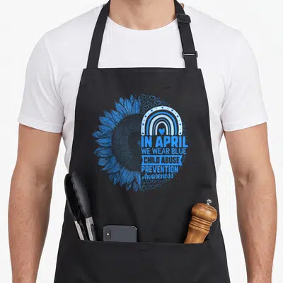 Abuse prevention april apron - Blue split sunflower with rainbow hearts and text In April We Wear Blue Child Abuse — shown on a black cotton canvas apron against a white background