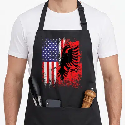 Albanian american flag apron - Split US flag and black eagle on red with distressed texture — shown on a black cotton canvas apron against a white background