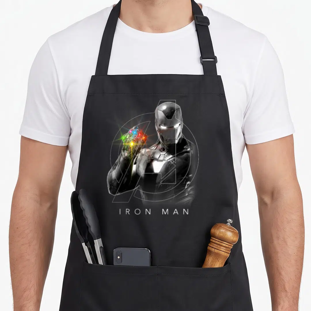 Endgame stone apron - Realistic Iron Man raising a gauntlet with colored stones and white text below — shown on a black cotton canvas apron against a white background