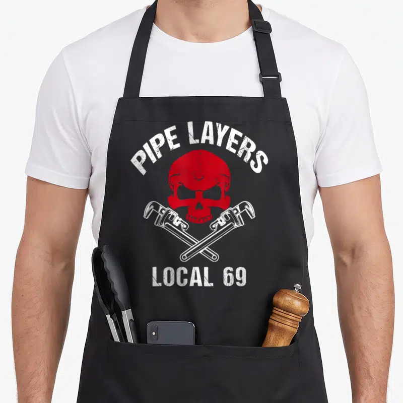 Local pipe apron - Red skull and crossed wrenches with PIPE LAYERS LOCAL 69 text — shown on a black cotton canvas apron against a white background