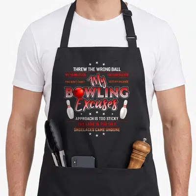 Funny excuse bowling apron - My BOWLING Excuses text with red ball, white pins, and excuse phrases — shown on a black cotton canvas apron against a white background