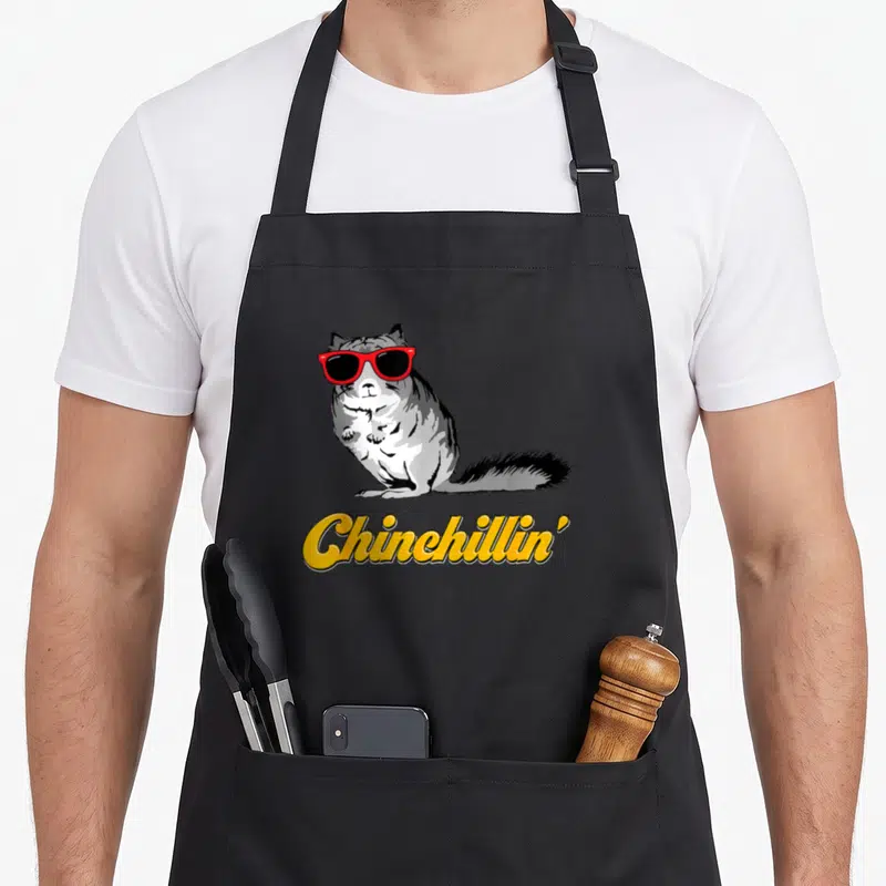 Funny chinchillin crazy chinchilla man apron - Grey chinchilla in red sunglasses above yellow Chinchillin text — shown on a black cotton canvas apron against a white background