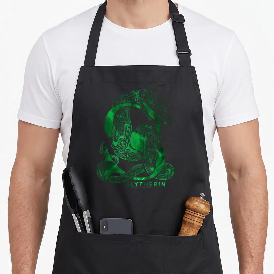 Funny novelty apron with pockets - Green snake coiled in S shape above SLYTHERIN text — shown on a black cotton canvas apron against a white background