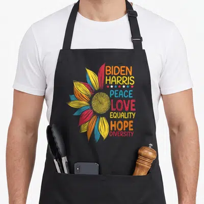 Biden peace apron - Colorful sunflower with stacked text BIDEN HARRIS PEACE LOVE EQUALITY HOPE DIVERSITY and small stars — shown on a black cotton canvas apron against a white background