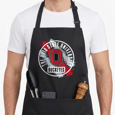 Funny paint apron - Red O logo in white circle with THE OHIO STATE UNIVERSITY text and grey paint splatter — shown on a black cotton canvas apron against a white background