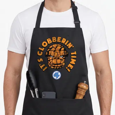 Fantastic face apron - Orange rocky head with arched text and blue number 4 logo — shown on a black cotton canvas apron against a white background