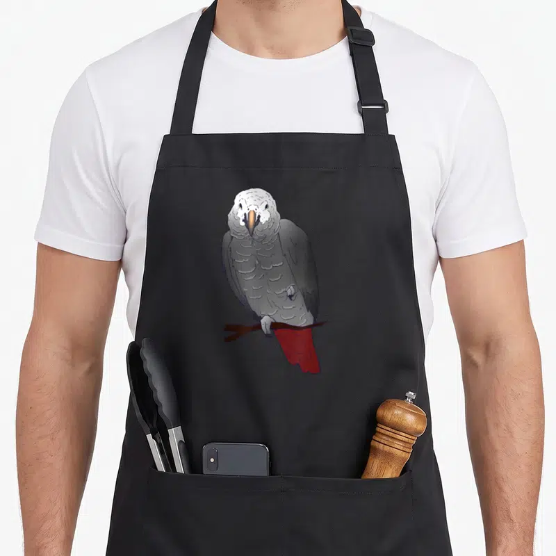 Perching african aprons - Grey parrot with white head and red tail perched on a brown cartoon branch — shown on a black cotton canvas apron against a white background