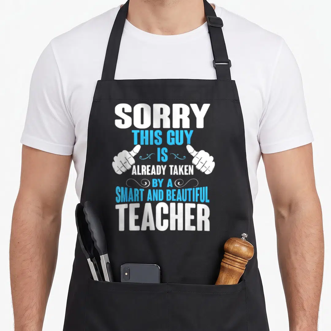 Taken teacher apron - Stacked white and cyan text with two pointing hands saying Sorry This Guy Is Already Taken — shown on a black cotton canvas apron against a white background