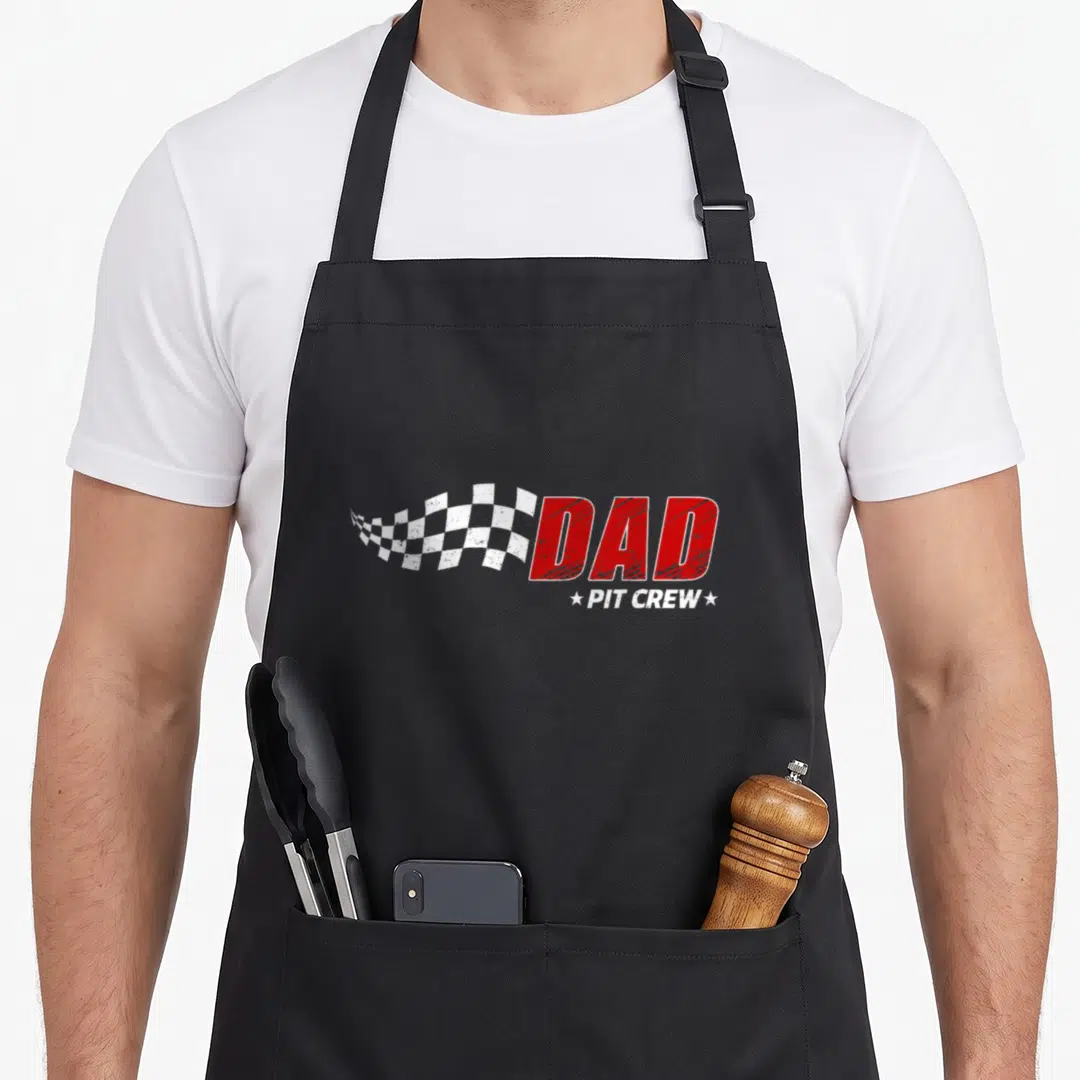 Pit crew car apron - Distressed red DAD text with white checkered flag and PIT CREW stars — shown on a black cotton canvas apron against a white background