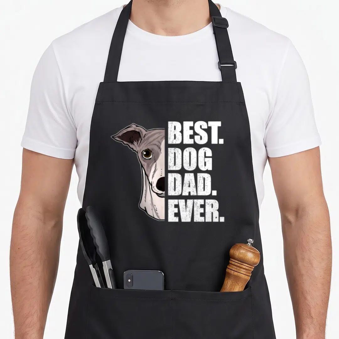 Whippet father day apron - Whippet face half-portrait next to stacked white text best dog dad ever in distressed style — shown on a black cotton canvas apron against a white background
