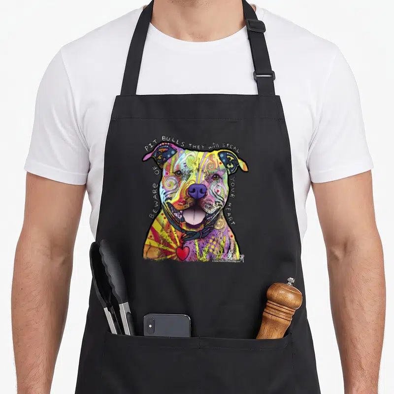 Beware dean russo aprons - Colorful cartoon pit bull with text 'Pit Bulls They Will Steal Beware Of Your Heart' and red — shown on a black cotton canvas apron against a white background