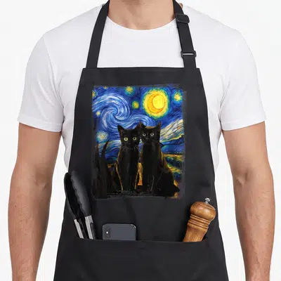 Painting van gogh apron - Two black cats sitting before a blue and yellow swirling starry night watercolor painting — shown on a black cotton canvas apron against a white background