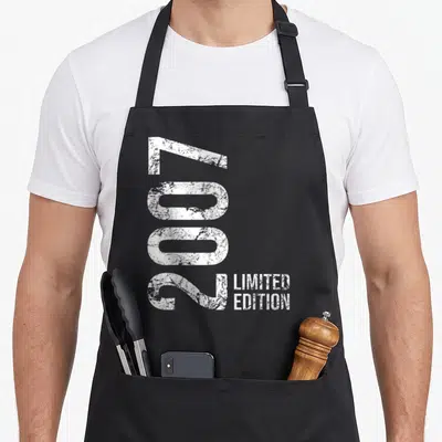 Limited 19th birthday apron - White 2007 limited edition typography stacked next to rotated year digits — shown on a black cotton canvas apron against a white background