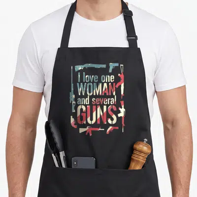 Several gun apron - Distressed red white blue text I love one WOMAN and several GUNS framed by gun silhouettes — shown on a black cotton canvas apron against a white background