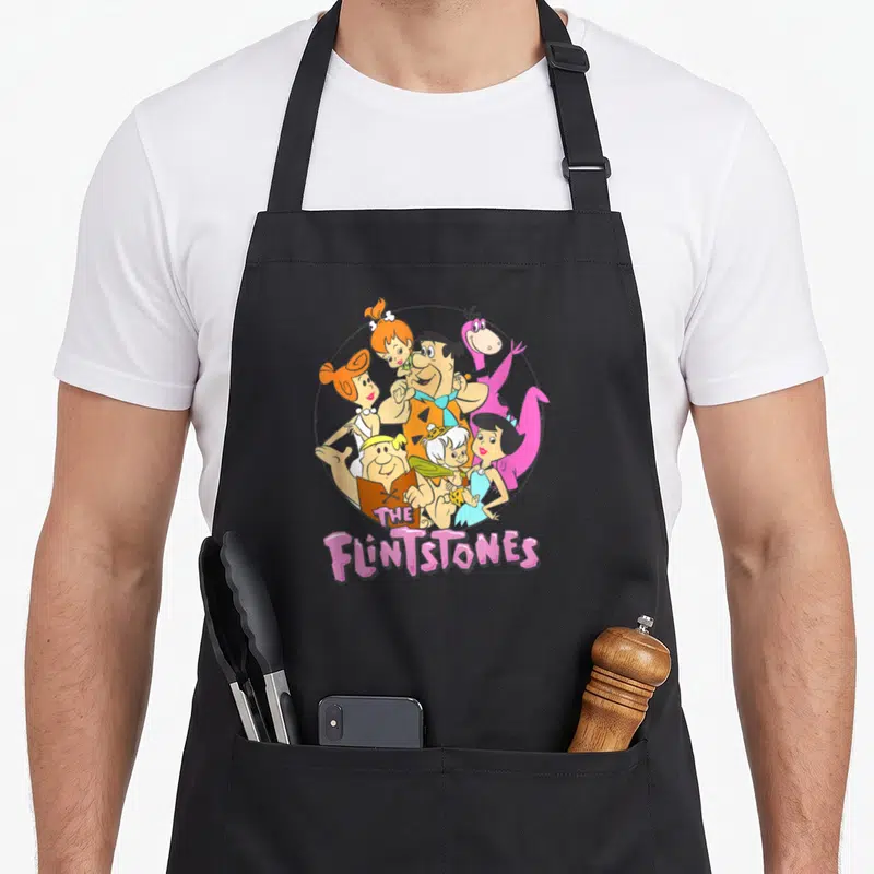 Shot family aprons - Flintstones cartoon characters in circle with pink title text — shown on a black cotton canvas apron against a white background