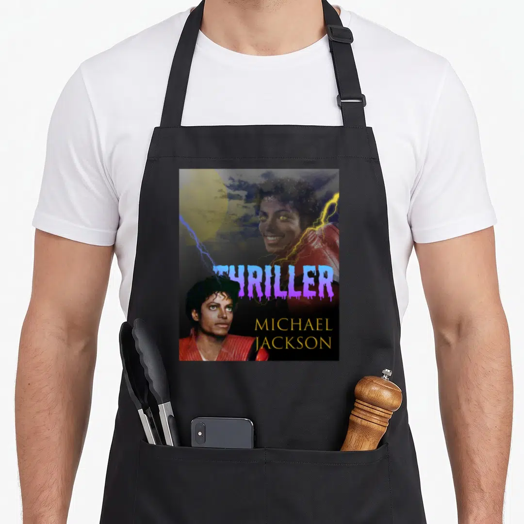 Performance michaels apron - Two Michael Jackson photos with purple THRILLER text and gold name on dark background — shown on a black cotton canvas apron against a white background