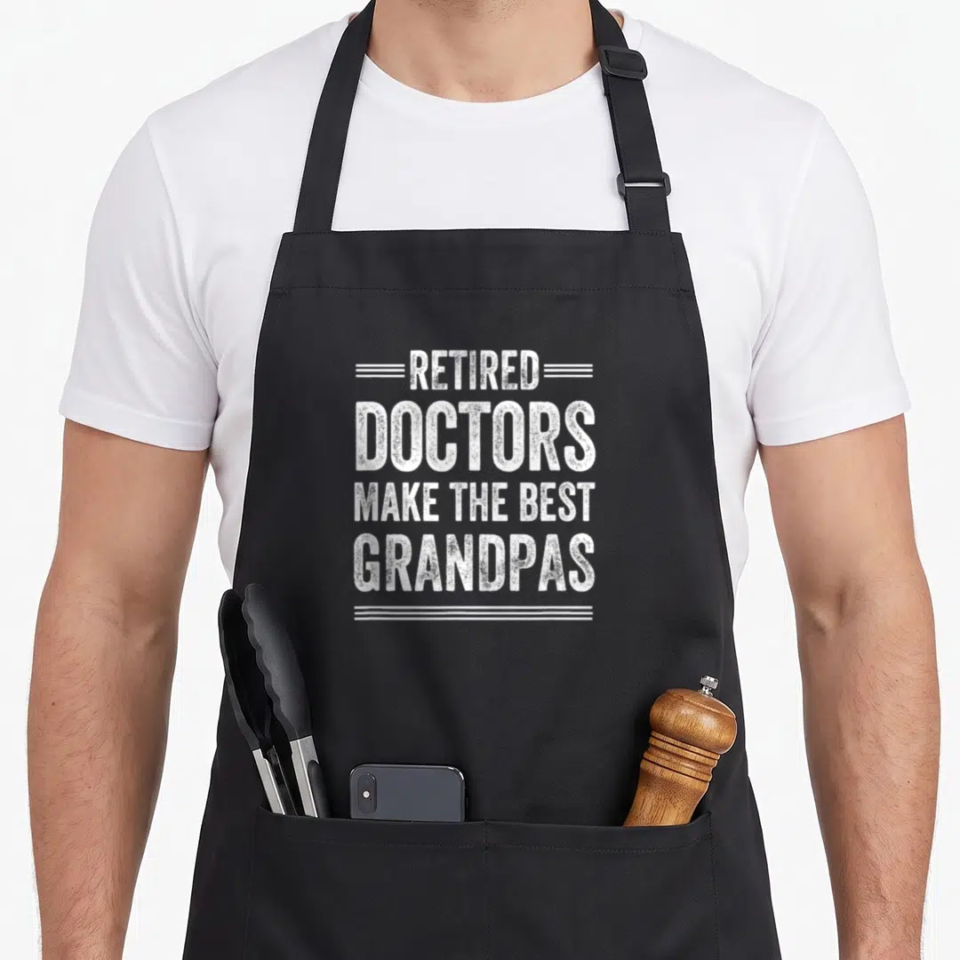 Pensioner doctor with apron - White distressed text reading RETIRED DOCTORS MAKE THE BEST GRANDPAS stacked between — shown on a black cotton canvas apron against a white background