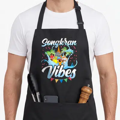 Songkran thai lover apron - Cartoon Songkran Vibes print with people, elephant, temple, and bunting in white, blue — shown on a black cotton canvas apron against a white background