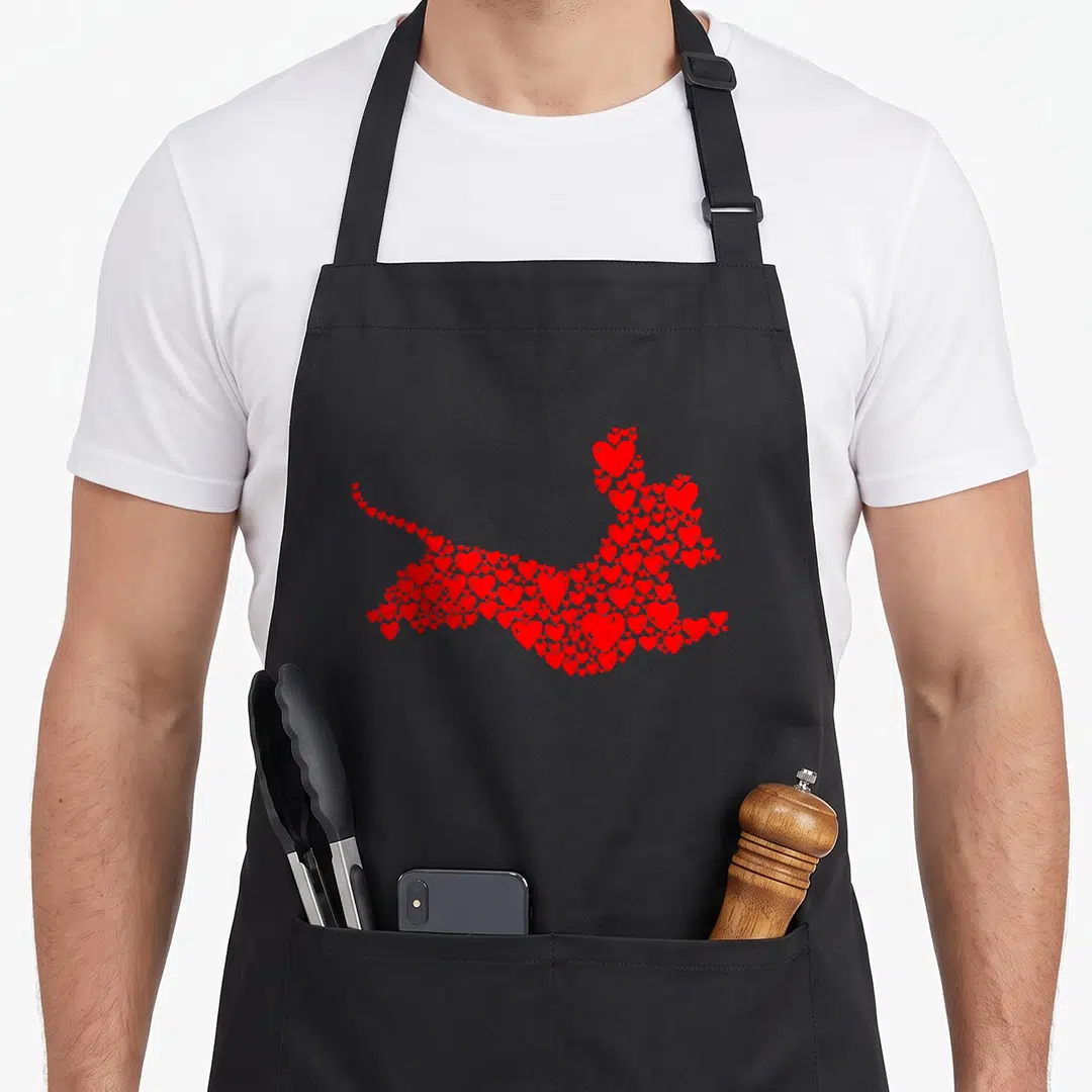Dog valentine's day apron - Dachshund silhouette formed by red hearts, minimalist style — shown on a black cotton canvas apron against a white background