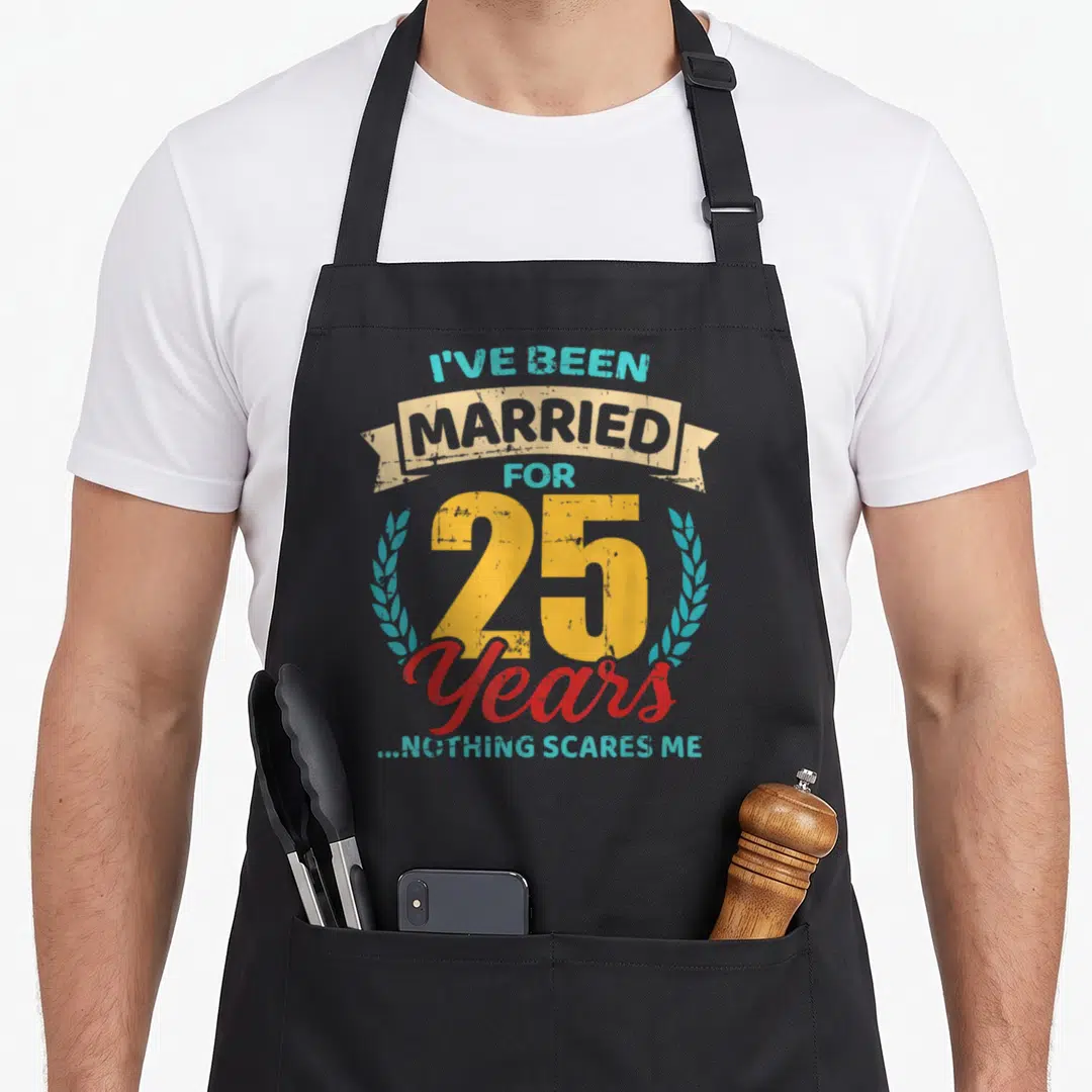 Married anniversary wedding apron - Distressed graphic reading I've been married for 25 years nothing scares me — shown on a black cotton canvas apron against a white background