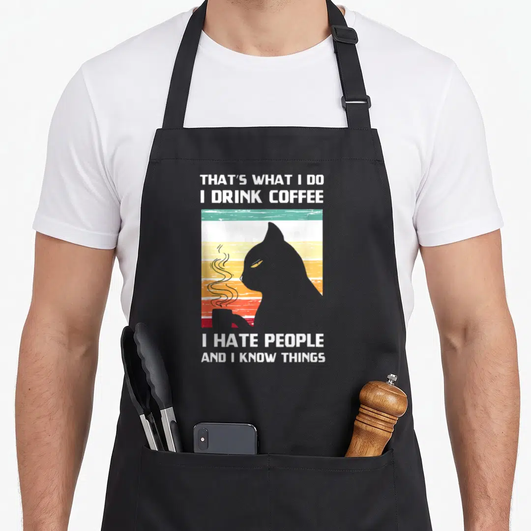 Drink coffee aprons - Retro cat silhouette holding steaming cup against striped sunset with white text — shown on a black cotton canvas apron against a white background