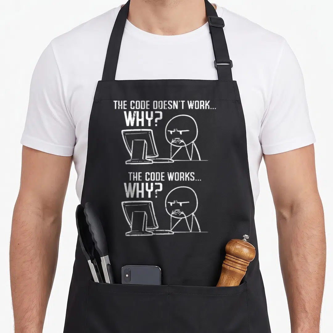 Programmer code coder apron - White text THE CODE DOESN'T WORK WHY and THE CODE WORKS WHY above two identical cartoon — shown on a black cotton canvas apron against a white background