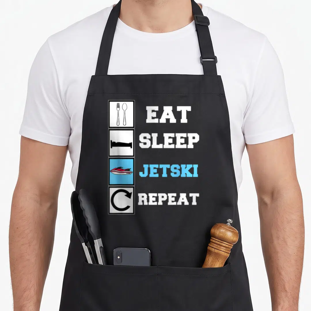Eat jetski apron - Four stacked icons with eat sleep jetski repeat text and red watercraft in blue square — shown on a black cotton canvas apron against a white background