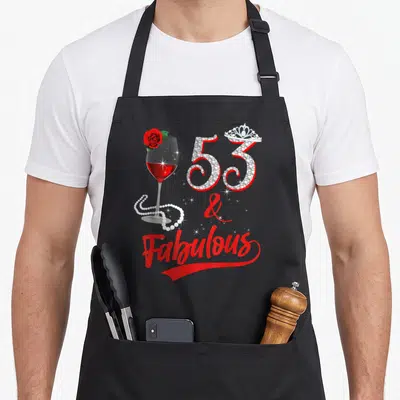 Fabulous wine apron - Crystal number 53 with tiara, red wine glass, pearls, and Fabulous text — shown on a black cotton canvas apron against a white background