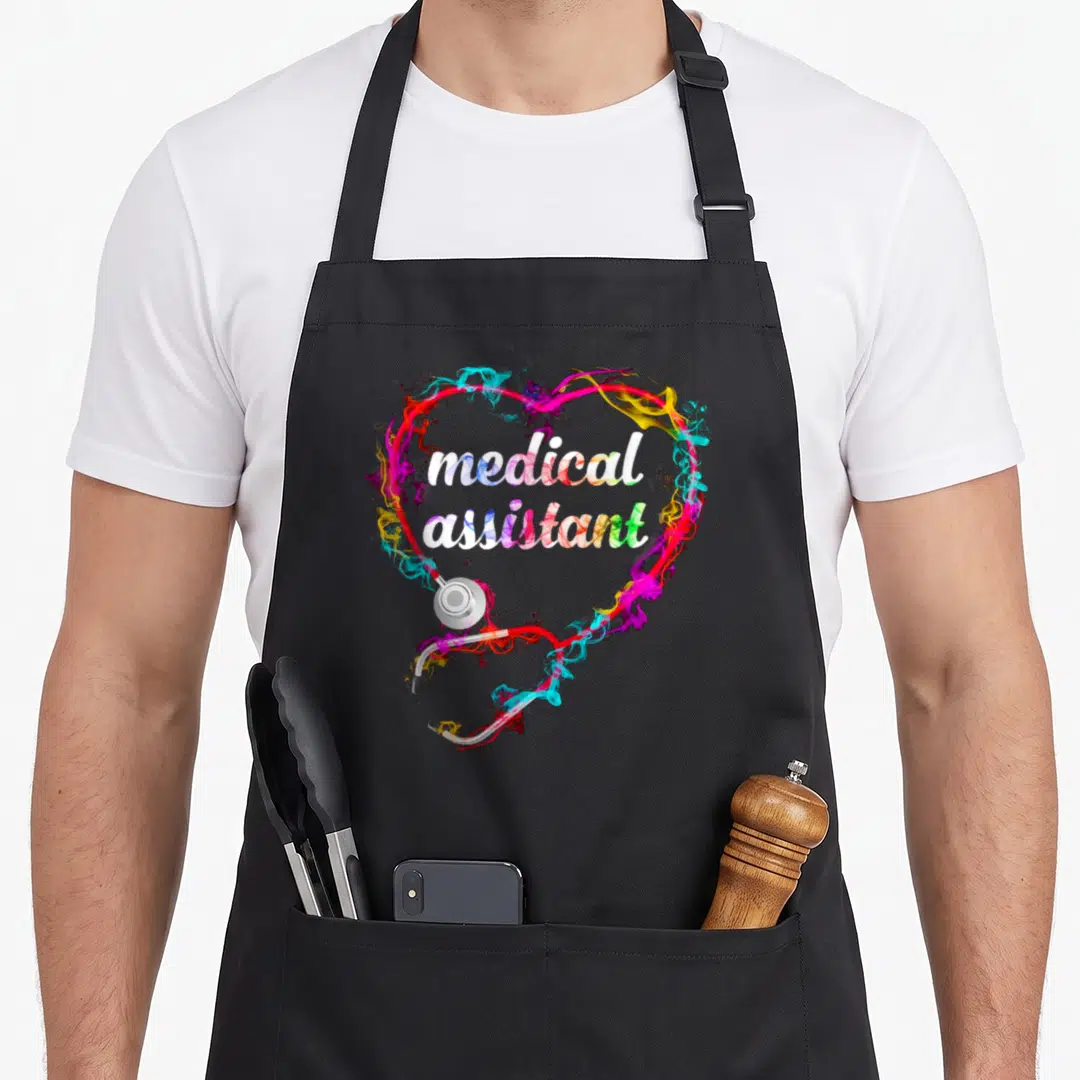 Medical colorful aprons - Stethoscope heart with multicolored smoke and medical assistant text in cartoon style — shown on a black cotton canvas apron against a white background
