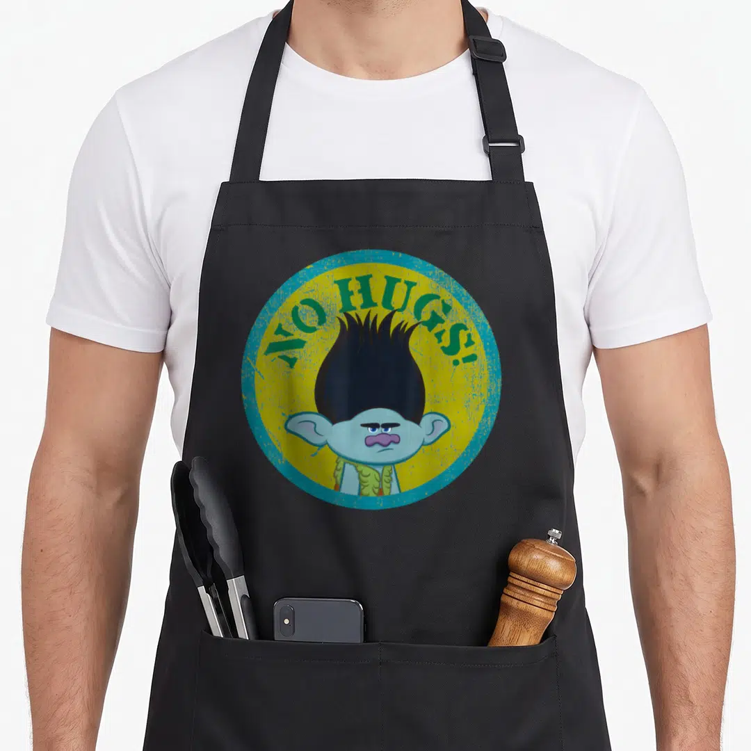 Hug troll apron - Grumpy blue cartoon troll in yellow circle with teal border and green text reading NO HUGS! — shown on a black cotton canvas apron against a white background
